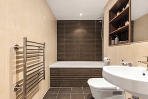 Ein modernes Badezimmer mit Badewanne, Toilette und Waschbecken.