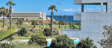Un resort con piscina, palmeras y vista al océano.