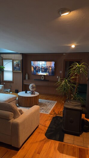 A living room with a television, a sofa, a coffee table, a globe, and a fireplace. - Clifford Luxury Retreat 3BR Self Check In Home (Northbridge)