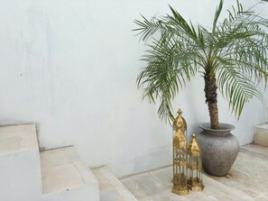 A potted palm tree, a large decorative vase, and two ornate lanterns against a plain wall. - La PAYANA House Penida (Penida Island)