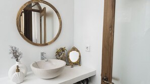 A bathroom with a round mirror, a white sink, a decorative vase, and a gold-framed mirror. - La PAYANA House Penida (Penida Island)