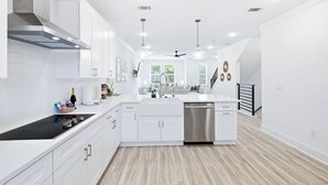 Una cucina moderna con mobili bianchi, una lavastoviglie in acciaio inossidabile e un piano cottura nero.