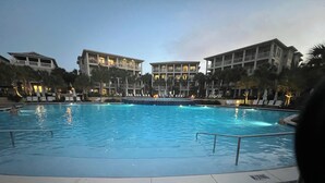 Una piscina con bordo piastrellato, circondata da edifici con balconi e aree relax all'aperto.