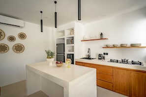 Eine moderne Küche mit einer zentralen Kochinsel, Holzschränken und einem eingebauten Backofen.