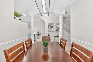 Ein Esszimmer mit Holztisch, Stühlen, einem Topf mit Pflanze und Bildern an den Wänden.