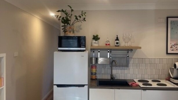 Cocina compacta con refrigerador, microondas, pileta y estufa.