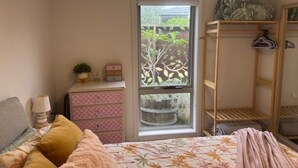 Un dormitorio con una cama, un aparador, un ventanal y una estantería de madera.