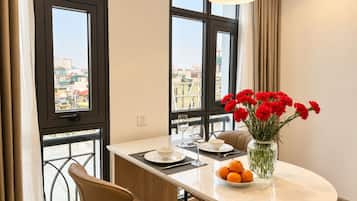 A modern dining area with a round table, chairs, a vase of flowers, and a bowl of oranges.