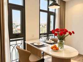 Un comedor moderno con una mesa redonda, sillas, un jarrón de flores y un cuenco de naranjas.