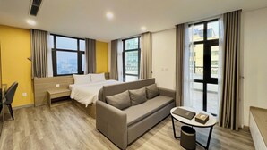 Une chambre d’hôtel avec un lit, un canapé, un bureau et de grandes fenêtres.