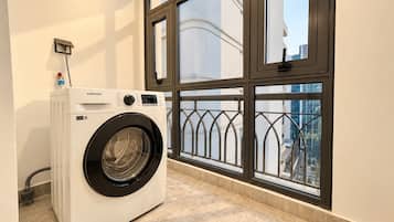 A front-loading Samsung washer in a room with a large window and a view of a building.