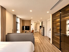 A hotel room with a bed, a TV, a kitchenette, and a sliding door closet.