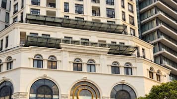 A multi-story building with a prominent entrance, large arched windows, and a sign reading 'GEM RESIDENCE.'