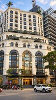A multi-story building with a prominent entrance, large arched windows, and a sign reading 'GEM RESIDENCE.'