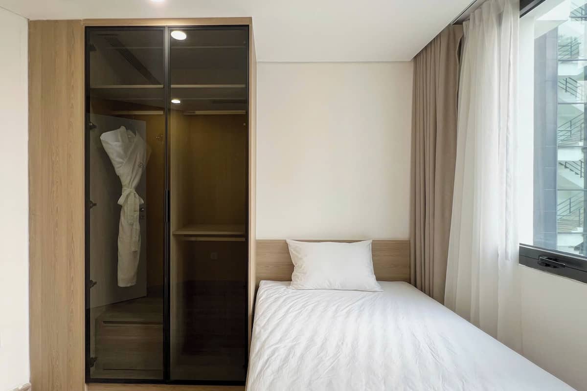 A bedroom with a bed, a wardrobe, and a window with curtains.