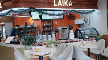 Interior de una cafetería con mostrador, zona de estar y un panel con la carta.