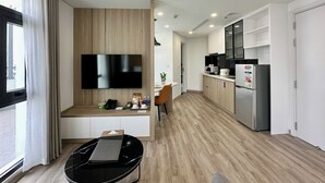 Une cuisine moderne équipée d’un téléviseur à écran plat, de meubles en bois, d’un réfrigérateur et d’un coin repas avec une chaise.