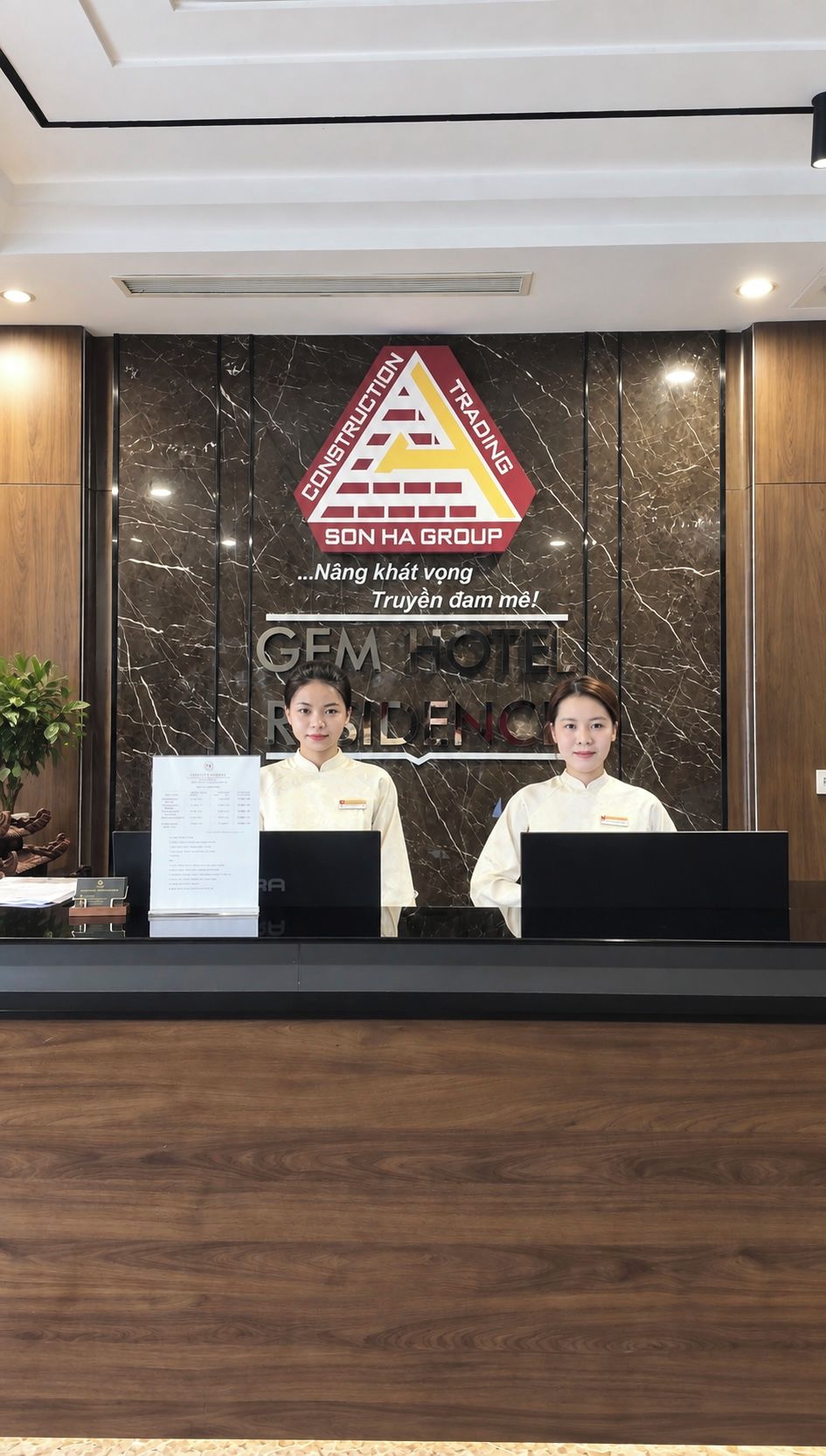 A reception desk with a logo for Son Ha Group and a sign for Gem Hotel.