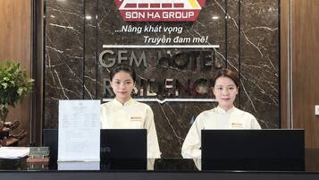 A reception desk with a logo for Son Ha Group and a sign for Gem Hotel.