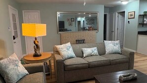 Ett vardagsrum med en soffa, ett soffbord, en lampa och en takfläkt.
