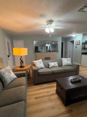 A living room with a sofa, a coffee table, a lamp, and a ceiling fan. - Captain's Corner, 4/2 w/Heated Pool & 4 kayaks Waterfront Canal Weeki Wachee (Spring Hill)