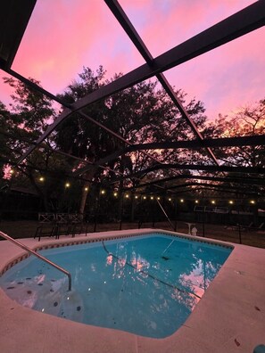 A swimming pool with a metal frame structure, surrounded by trees and string lights. - Captain's Corner, 4/2 w/Heated Pool & 4 kayaks Waterfront Canal Weeki Wachee (Spring Hill)