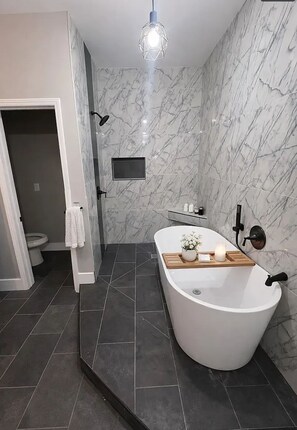 A modern bathroom with a freestanding bathtub, a shower area, a toilet, and a vanity with a mirror. - Spacious 4-bedroom townhome in tranquil Atlanta with AC (Atlanta)