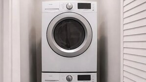 Pesuhuone, jossa on kaksi päällekkäin asennettua, etupuolelta täytettävää pyykinpesukonetta.