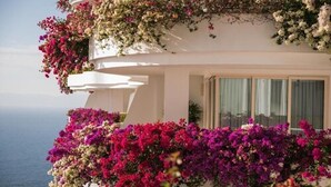 Ein mehrstöckiges Gebäude mit Balkonen, die mit Blumen geschmückt sind, mit Blick auf ein Gewässer.