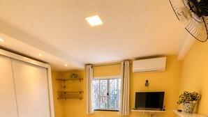 A hotel room with a bed, a desk, a chair, a TV, and a window with curtains. - Casa confortável (Belém)
