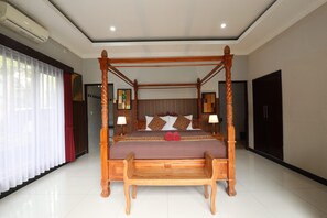 A four-poster bed with a wooden frame, a large window with sheer curtains, and a wall-mounted air conditioner. - Puri Bisma Ubud (Ubud)