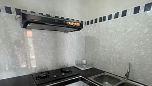 Una cocina con estufa a gas, dos fregaderos, encimera negra y salpicadero con diseño geométrico.