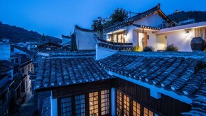 A traditional building with a tiled roof, a wooden structure with a window, and a modern building with a light fixture. - Fenghuang Bahaobieyuan (Xiangxi)