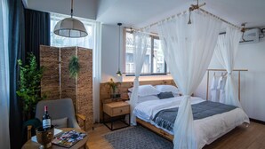 A bedroom with a bed, bedside table, chair, and a window with curtains. - Fenghuang Bahaobieyuan (Xiangxi)
