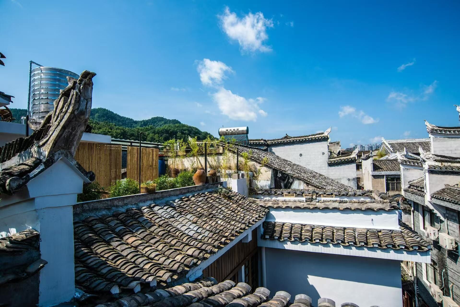 Traditional architecture with tiled roofs, a wooden structure, and a modern building in the background.