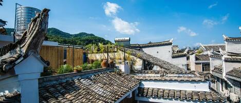 Traditional architecture with tiled roofs, a wooden structure, and a modern building in the background.