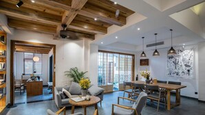 A spacious living area with a high ceiling, wooden beams, a dining table, and a sofa. - Fenghuang Bahaobieyuan (Xiangxi)