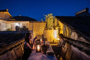 A traditional courtyard with a table, chairs, and a candle-lit table setting. - Fenghuang Bahaobieyuan (Xiangxi)