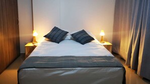 Een hotelkamer met een bed, twee bedlampen en een gordijn.
