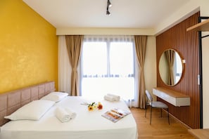 A hotel room with a bed, a desk, a chair, a mirror, and a window with curtains. - La Dimora Azzurra 101, Vlore, Albania (Vlore)