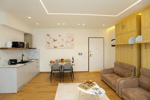 A modern kitchen with a marble countertop, a dining area with a table set for four, and a brown leather sofa. - La Dimora Azzurra 101, Vlore, Albania (Vlore)