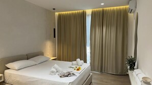 Een moderne hotelkamer met een groot bed, een nachtkastje, een airconditioning en een raam met gordijnen.