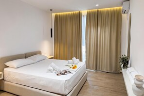A hotel room with a bed, a bedside table, a window with curtains, and a potted plant. - La Dimora Azzurra 601, Vlore, Albania (Vlore)