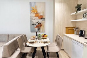 A modern dining area with a round table, four chairs, a fruit bowl, and a wine bottle. - La Dimora Azzurra 601, Vlore, Albania (Vlore)
