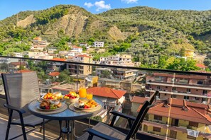 A balcony with a table set for breakfast, overlooking a hillside town with buildings and greenery. - La Dimora Azzurra 601, Vlore, Albania (Vlore)