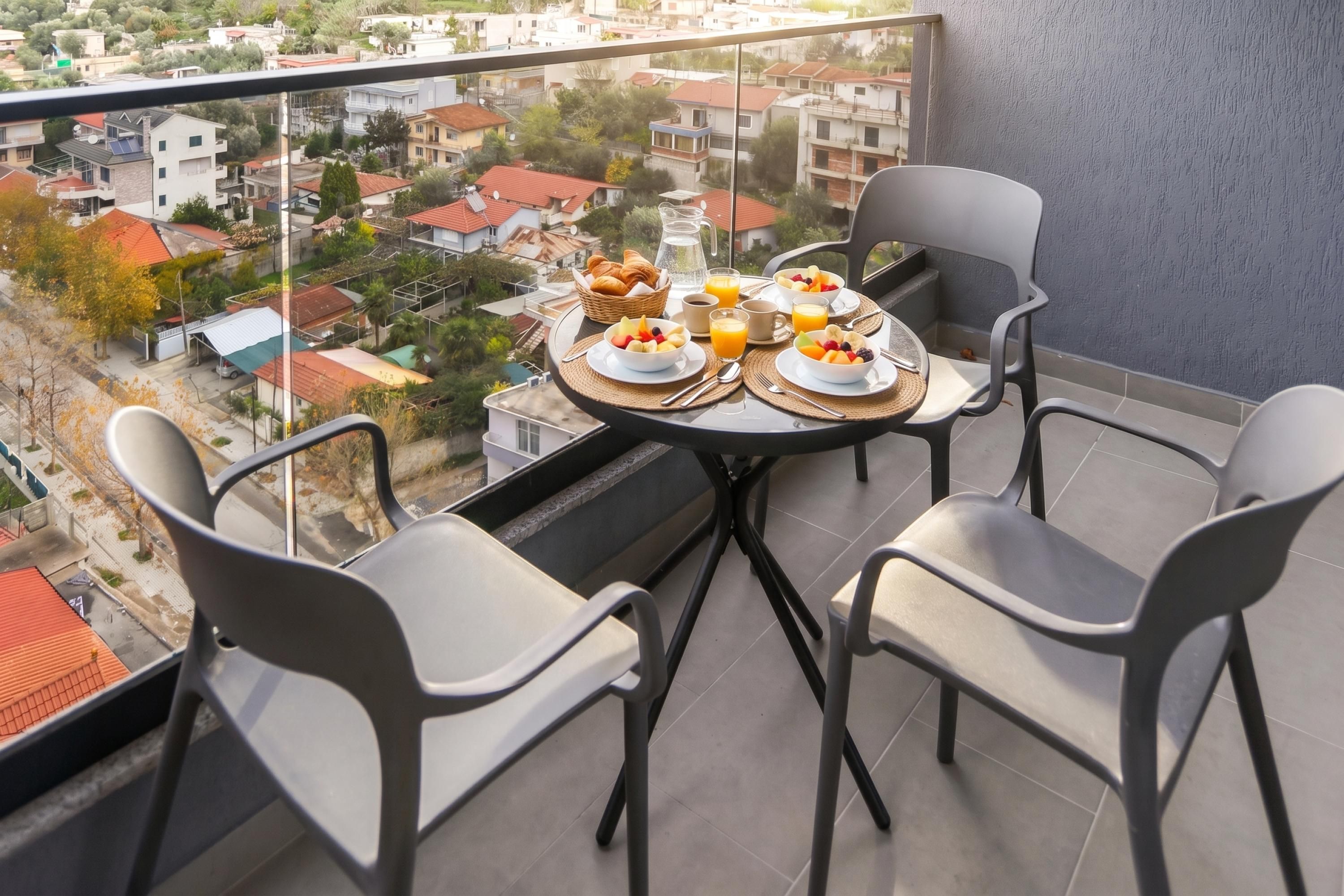 A balcony with a table set for breakfast, overlooking a residential area.