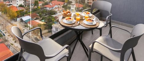 A balcony with a table set for breakfast, overlooking a residential area.