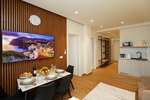 Un espace de repas moderne avec un mur lambrissé en bois, un téléviseur à écran plat et une vue sur une ville côtière.
