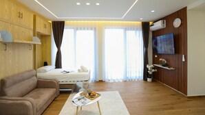 Una habitación de hotel moderna con cama, sofá, televisión y paneles de madera.
