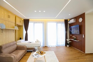 Ein modernes Hotelzimmer mit einer Couch, einem Bett, einem Fernseher und einer Holzwand.